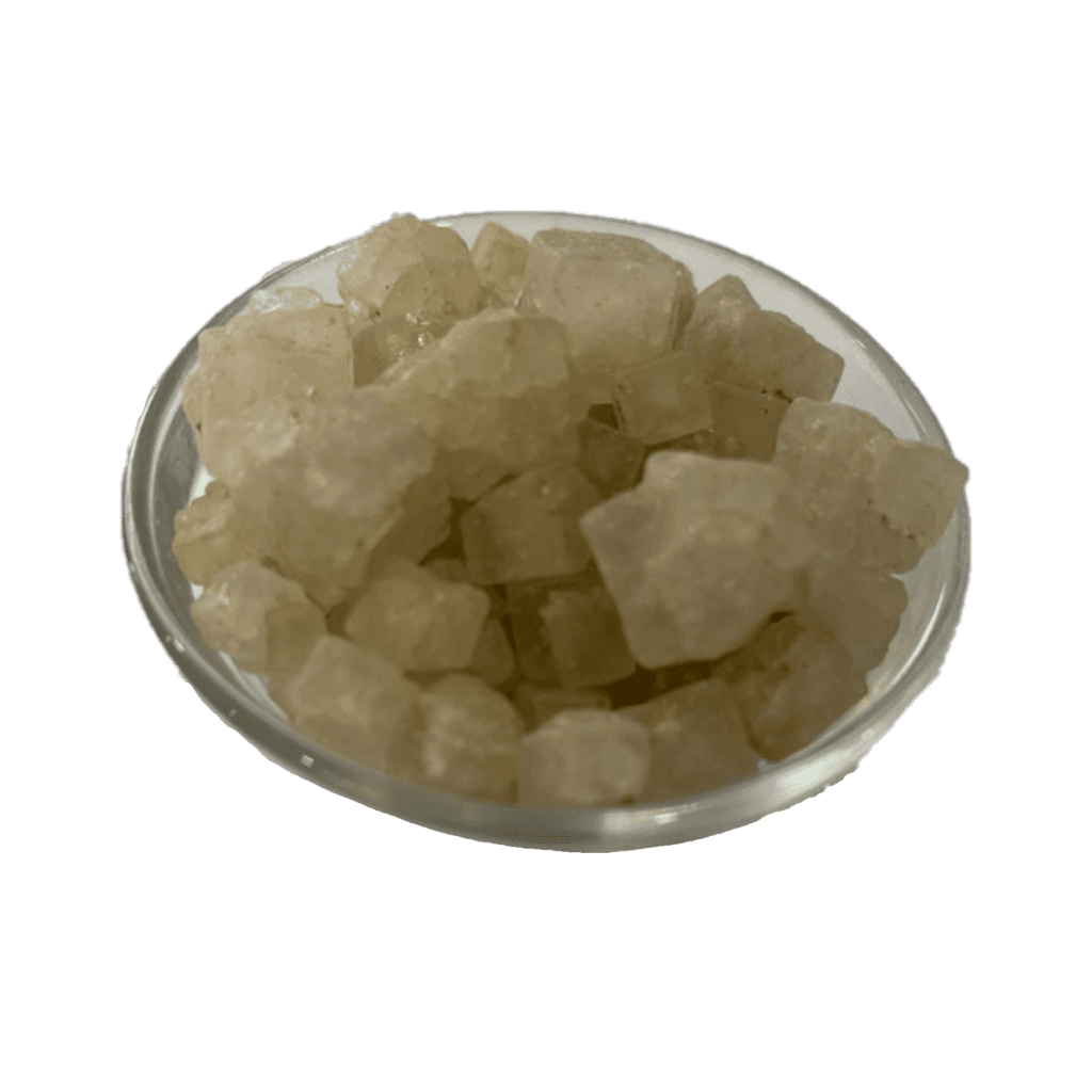 A bowl filled with brown rocksalt cubes on a green background.